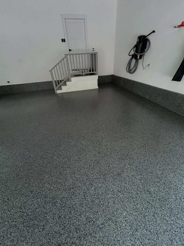 Dark grey flaked epoxy floor, basement interior with stair railing