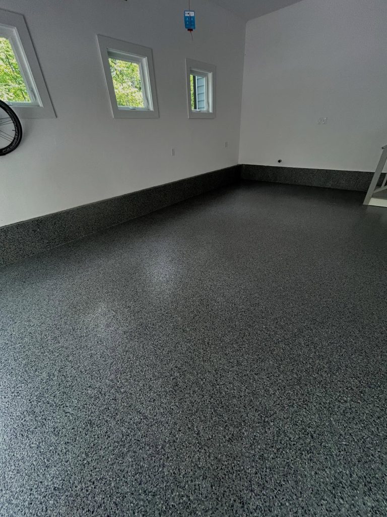 Dark grey flaked epoxy floor, finished basement with natural light from windows