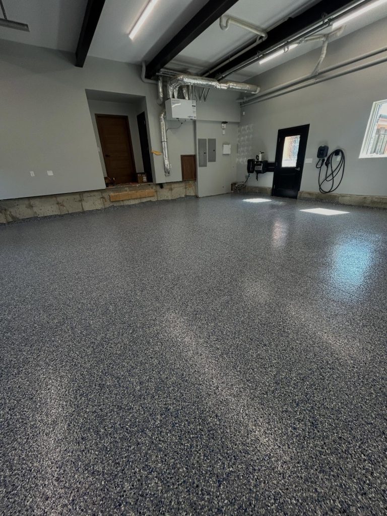 Grey flaked epoxy garage floor with side entry door and utility panel