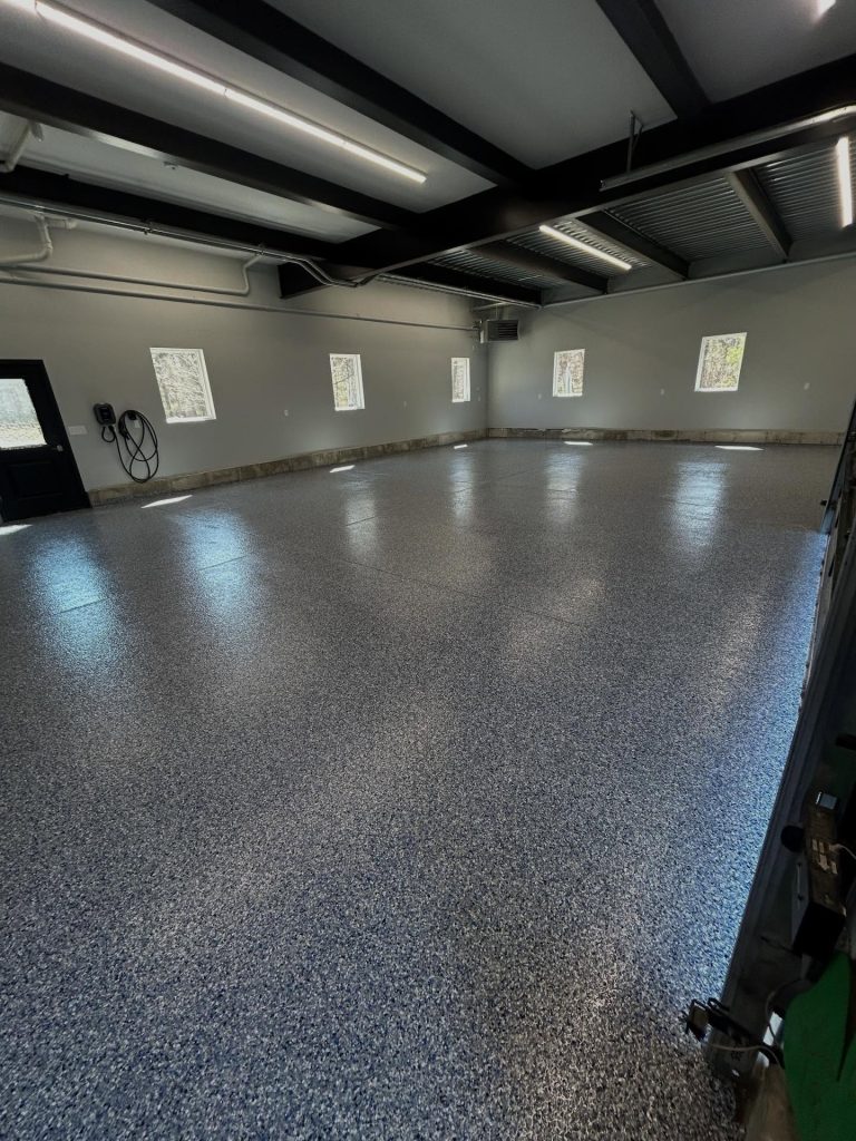 Grey flaked epoxy garage floor, wide view with black steel beams overhead