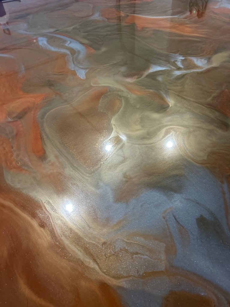 Metallic epoxy floor with copper, silver, and orange swirl, close-up detail