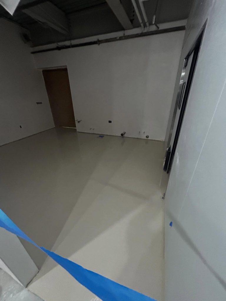 Solid white epoxy floor in a commercial interior with doors and clean walls